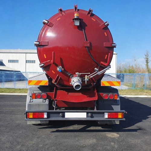 Naczepa asenizacyjna na ciężarówce MAN, stojąca na placu przemysłowym.